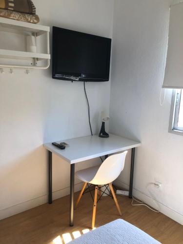 a desk with a chair and a tv on a wall at MEDITERRANEAN HOUSE - Habitaciones Privadas en Casa Compartida in Mairena del Aljarafe