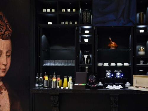 ディジョンにあるGrand Hôtel La Cloche Dijon - MGallery Collectionのアルコールのボトルが置かれたカウンターのある暗い部屋