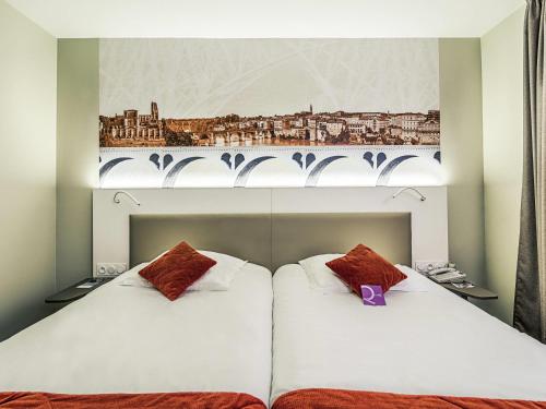 two beds in a hotel room with a picture on the wall at Mercure Albi Rives du Tarn in Albi