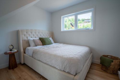 a white bedroom with a bed with a window at Absolute comfort with spa - Le Panorama in Saint Come