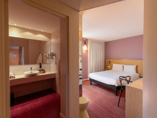a hotel room with a bed and a bathroom at ibis Styles Le Puy en Velay in Le Puy en Velay