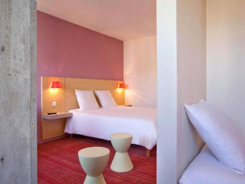 a hotel room with a large white bed with two pillows at ibis Styles Le Puy en Velay in Le Puy en Velay