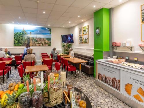 a restaurant with people sitting at tables and a green wall at ibis Styles Le Puy en Velay in Le Puy en Velay