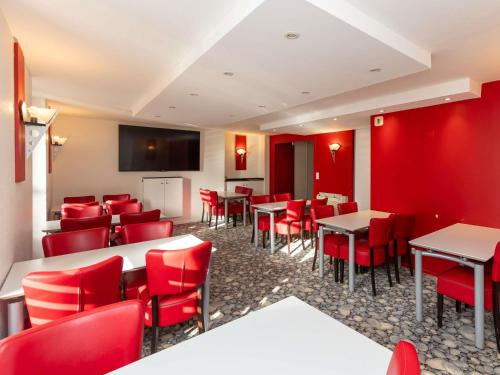 a restaurant with red chairs and tables and a screen at ibis Styles Le Puy en Velay in Le Puy en Velay