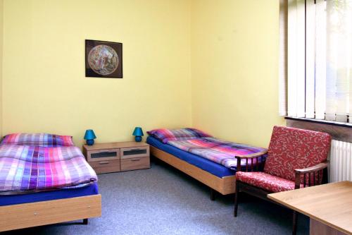 a room with two beds and a chair and a table at Penzion Muflon in Bělá nad Radbuzou