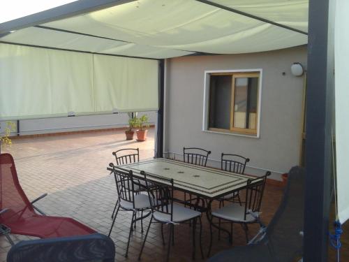 a patio with a table and chairs in a room at Holiday House Etna Mare Taormina in Mascali