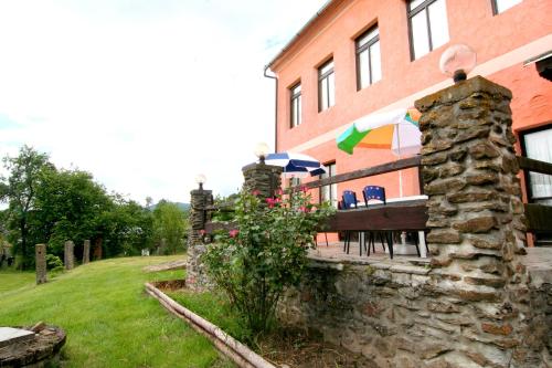 a brick building with a bench and an umbrella at Penzion Muflon in Bělá nad Radbuzou