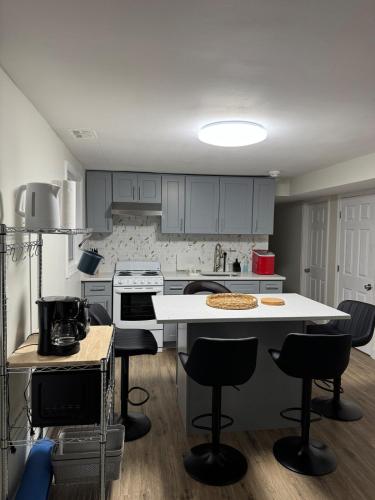 a kitchen with a white counter and chairs in it at Comfort Stay by Stony Brook University & Hospital in Centereach