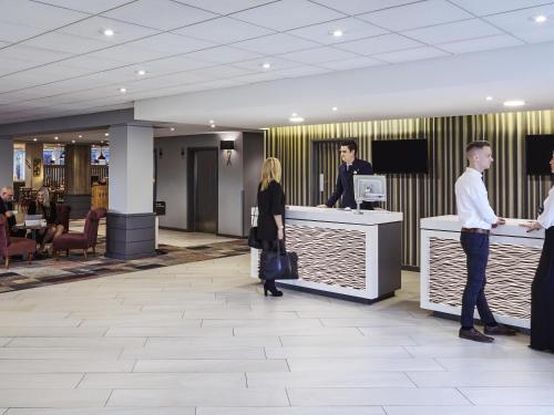 a group of people standing at a counter in a lobby at Novotel Wolverhampton City Centre in Wolverhampton