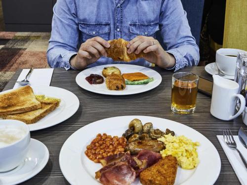 a person sitting at a table with plates of food at Novotel Wolverhampton City Centre in Wolverhampton
