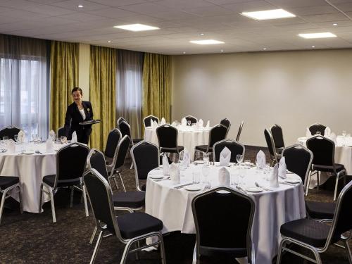 a man standing in a room with tables and chairs at Novotel Wolverhampton City Centre in Wolverhampton