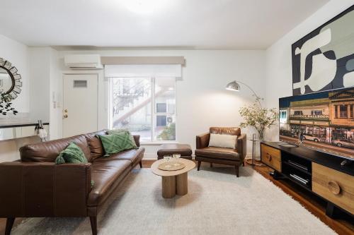 a living room with a leather couch and a tv at StayCentral - Brunswick Vibe Parkville in Melbourne