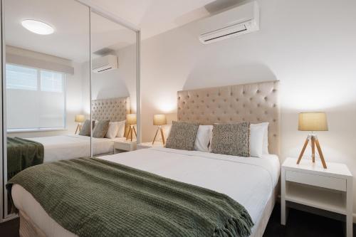 Un dormitorio con dos camas y un gran espejo. en StayCentral - Brunswick Vibe Parkville, en Melbourne