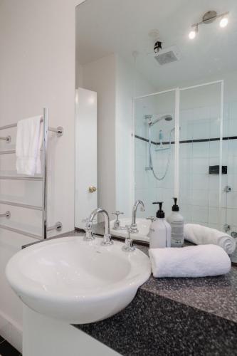 a white bathroom with a sink and a mirror at StayCentral - Brunswick Vibe Parkville in Melbourne