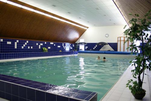 a swimming pool with two people in the water at Hotel Tanecnica in Pustevny