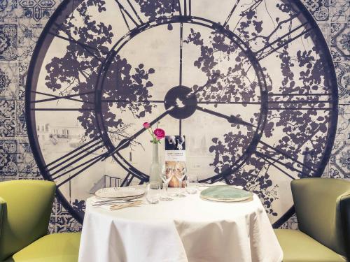 a table with a clock on the wall at Mercure Bourg En Bresse in Bourg-en-Bresse