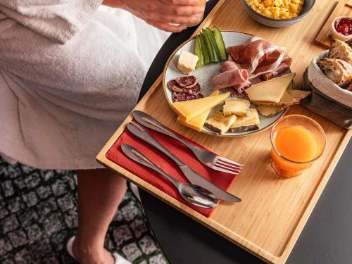a woman sitting at a table with a plate of food at Mercure Bourg En Bresse in Bourg-en-Bresse