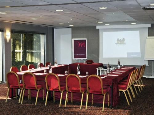 a conference room with a long table and red chairs at Mercure Bourg En Bresse in Bourg-en-Bresse