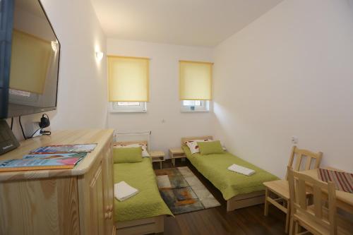 ザコパネにあるApartament Giewont Krupowkiの緑の椅子2脚とテレビが備わる小さな客室です。