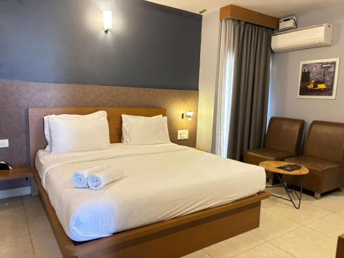 a hotel room with a large bed and a chair at Air Avenue Hotel - Airport in Devanahalli-Bangalore