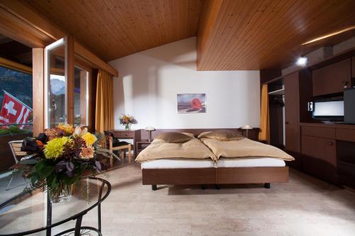 1 dormitorio con 1 cama y 1 mesa con flores en Jungfrau Hotel, en Wilderswil