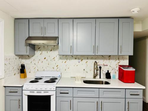 a kitchen with white cabinets and a sink at Comfort Stay by Stony Brook University & Hospital in Centereach