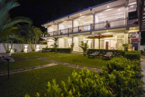 a large white building with a courtyard at night at Weleges Place in Hikkaduwa