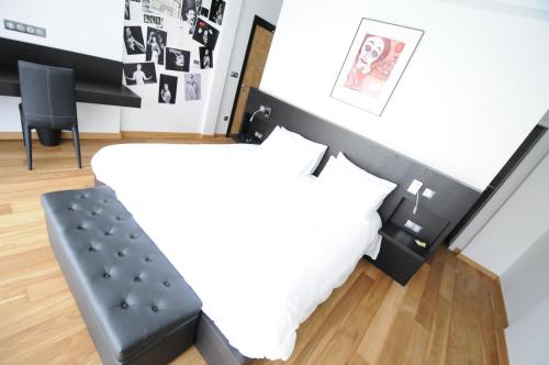 a bedroom with a black and white bed and a black bench at Logis Hotel Restaurant Au Boeuf Rouge in Niederschaeffolsheim
