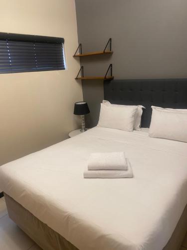 a large white bed with a white towel on it at Easy Stay - The Vantage Rosebank in Johannesburg