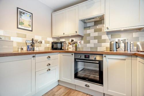 a kitchen with white cabinets and a stove at 2 Hammond Square in Weybourne