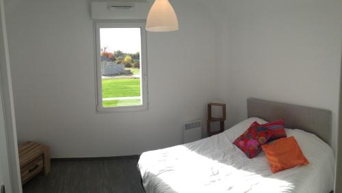 a white bedroom with a bed with a window at Les Portes de la baie in Grand-Laviers