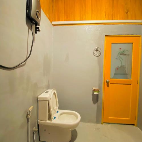 a bathroom with a toilet and a yellow door at Sigiriya Ranasinghe Nature Villa & Cabana in Sigiriya