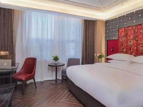 a bedroom with a large white bed and a red chair at Jinjiang Metropolo Hotel - Taizhou Wanda Plaza in Taizhou