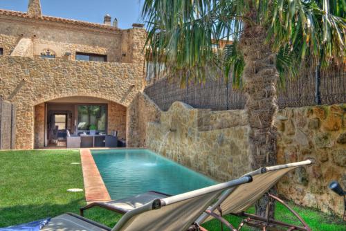 a villa with a swimming pool and a palm tree at Can Caranta in Pals