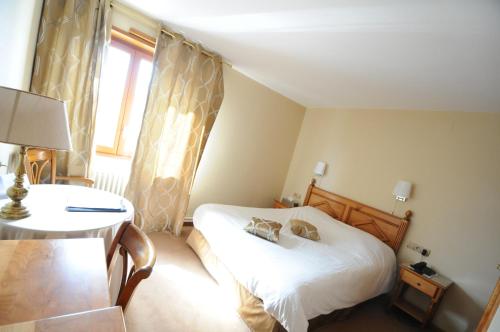 a bedroom with a bed and a table and a window at Logis Hotel Restaurant Au Boeuf Rouge in Niederschaeffolsheim