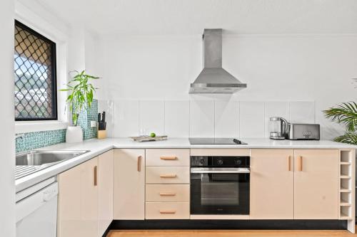 a white kitchen with a stove and a sink at Aurora in Lennox Head