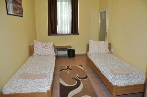 a room with two beds and a table in it at Guest House Best Food in Subotica
