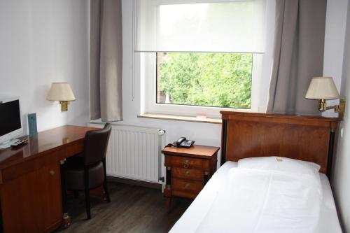 Schlafzimmer mit einem Bett, einem Schreibtisch und einem Fenster in der Unterkunft Hotel Schwarzer Adler in Moers