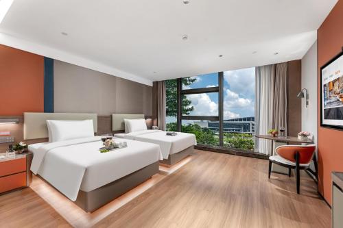 a hotel room with two beds and a tv at Huankai Hotel Pazhou Exhibition Center in Guangzhou