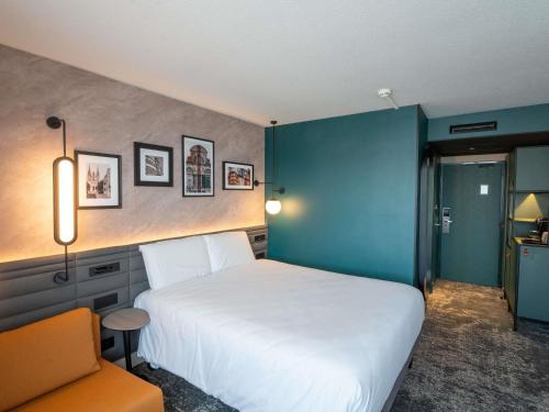 a bedroom with a white bed and a blue wall at Novotel Angers Lac de Maine in Angers