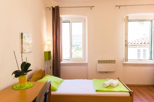 a bedroom with a bed and two windows at Apartment Mia in Rijeka