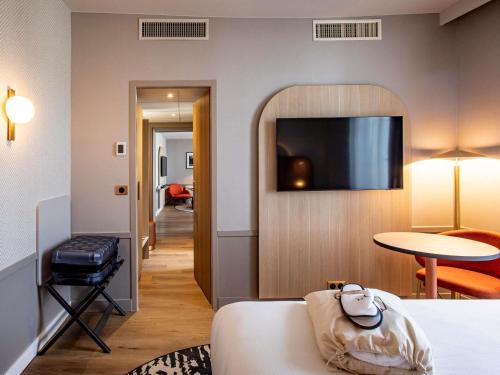 a hotel room with a bed and a flat screen tv at Mercure Angoulême Hôtel de France in Angoulême