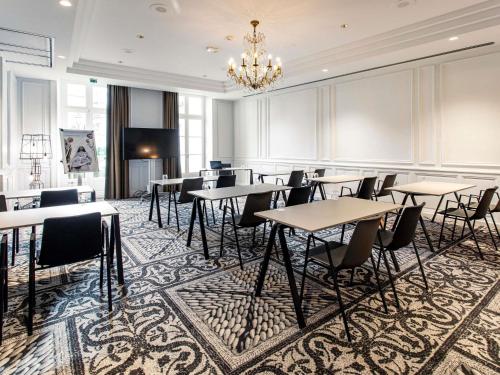 a dining room with tables and chairs and a chandelier at Mercure Angoulême Hôtel de France in Angoulême