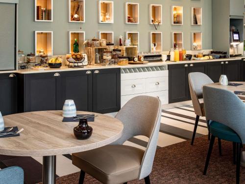 a kitchen with tables and chairs and mirrors at Mercure Angoulême Hôtel de France in Angoulême