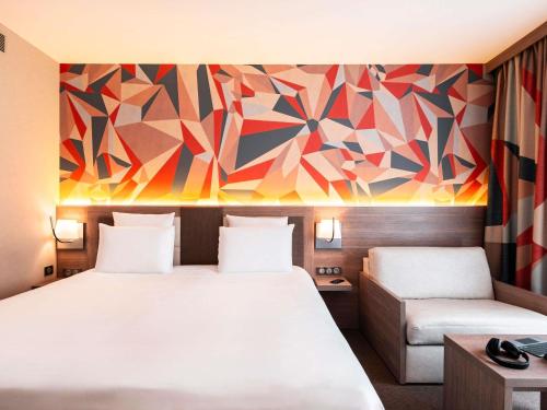 a hotel room with two beds and a colorful wall at Mercure Bayeux Omaha Beach in Port-en-Bessin-Huppain