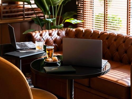 a coffee table with a laptop on a leather couch at Mercure Bayeux Omaha Beach in Port-en-Bessin-Huppain