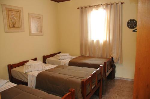 a room with three beds and a window at Hotel Fazenda Santa Maria in Serra Negra