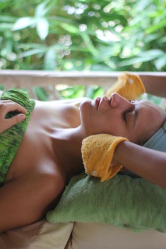 a woman laying on a couch with a towel on her face at The Griya Villas and Spa in Amed