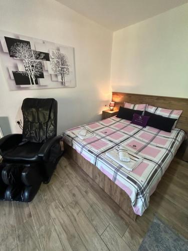 a bedroom with a large bed and a black chair at Vila Simona in Mavrovo