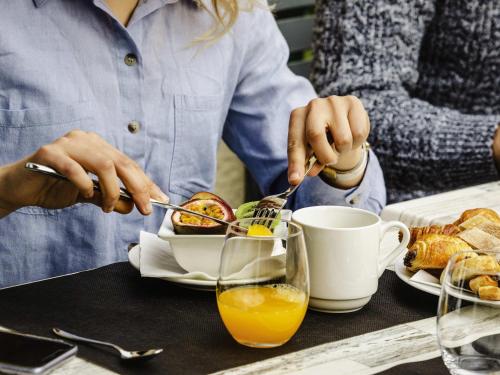 a person eating food at a table with a plate of food at Mercure Cabourg Hôtel & Spa in Cabourg